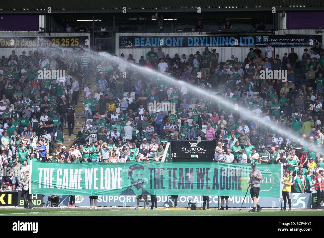 Miron Muslic, Manager von Plymouth Argyle, steht auf einem Banner vor dem Spiel mit der Aufschrift „The Game We Love, the Team We Adore“ Stockfoto
