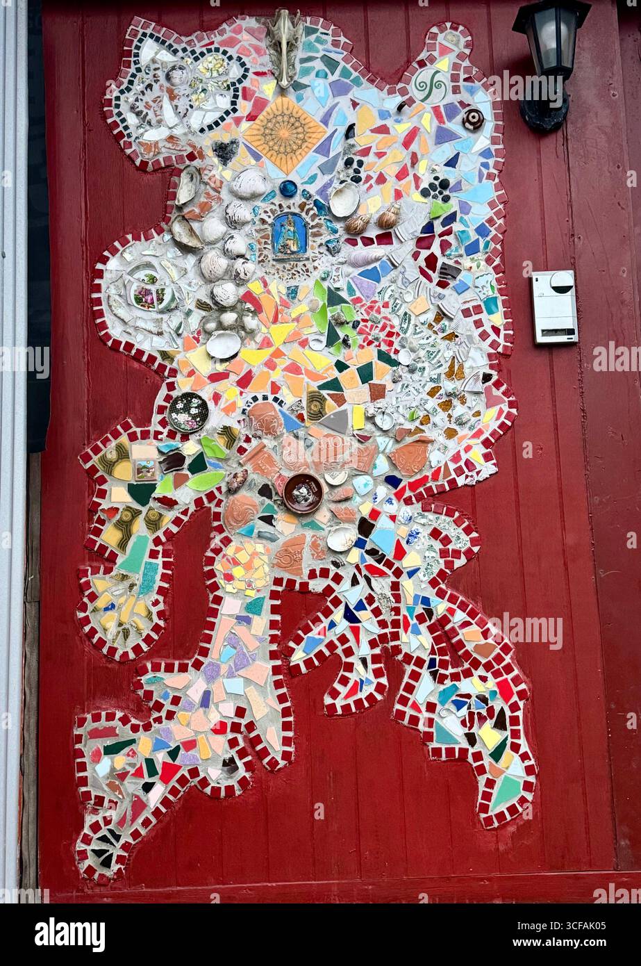 Eine rote Tür mit wunderschönen und farbenfrohen Mosaiken in Reykjavik. - Smartphone-aufgenommenes Stockfoto