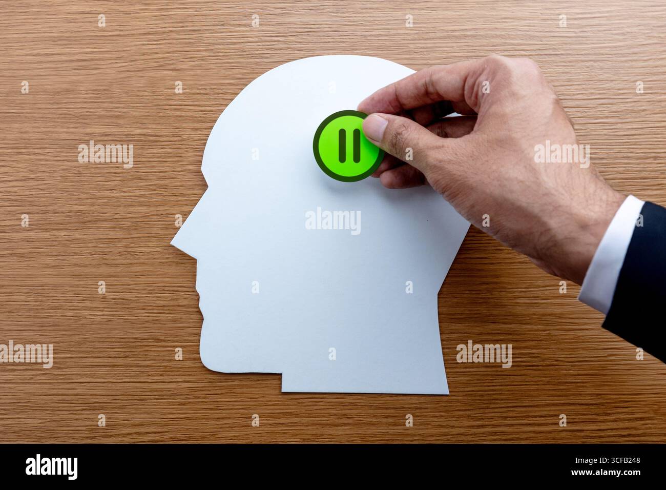 Ein kopfförmiger Ausschnitt und eine grüne Taste mit einem Pausensymbol. Pausen, Pausen, Stressmanagement und Achtsamkeitskonzept. Stockfoto