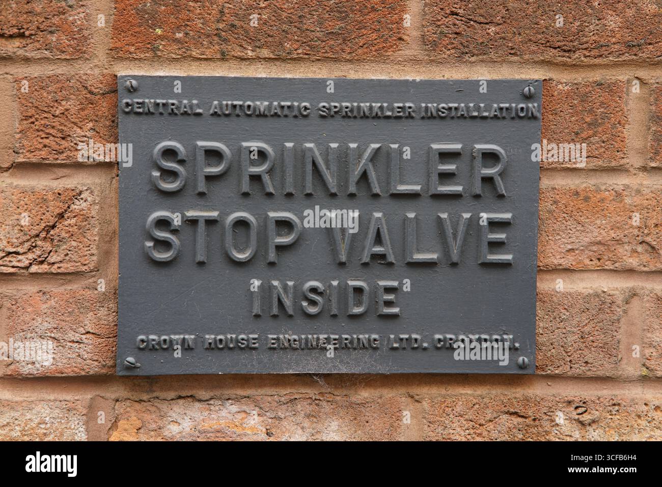 Schild mit metallischem Sprinkler-Absperrventil vor rustikalem Hintergrund. Redhill, England Stockfoto