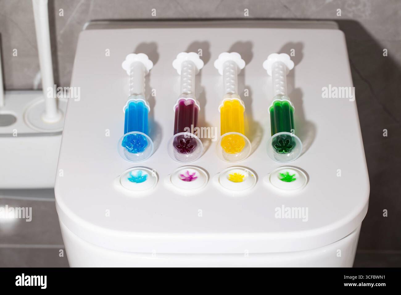 Ein Set mehrfarbiger Spritzen mit verschiedenen Düften auf der Toilettenschüssel in der Toilette zur Reinigung und Desinfektion. Hygiene und antibakterielle Wirkung Stockfoto