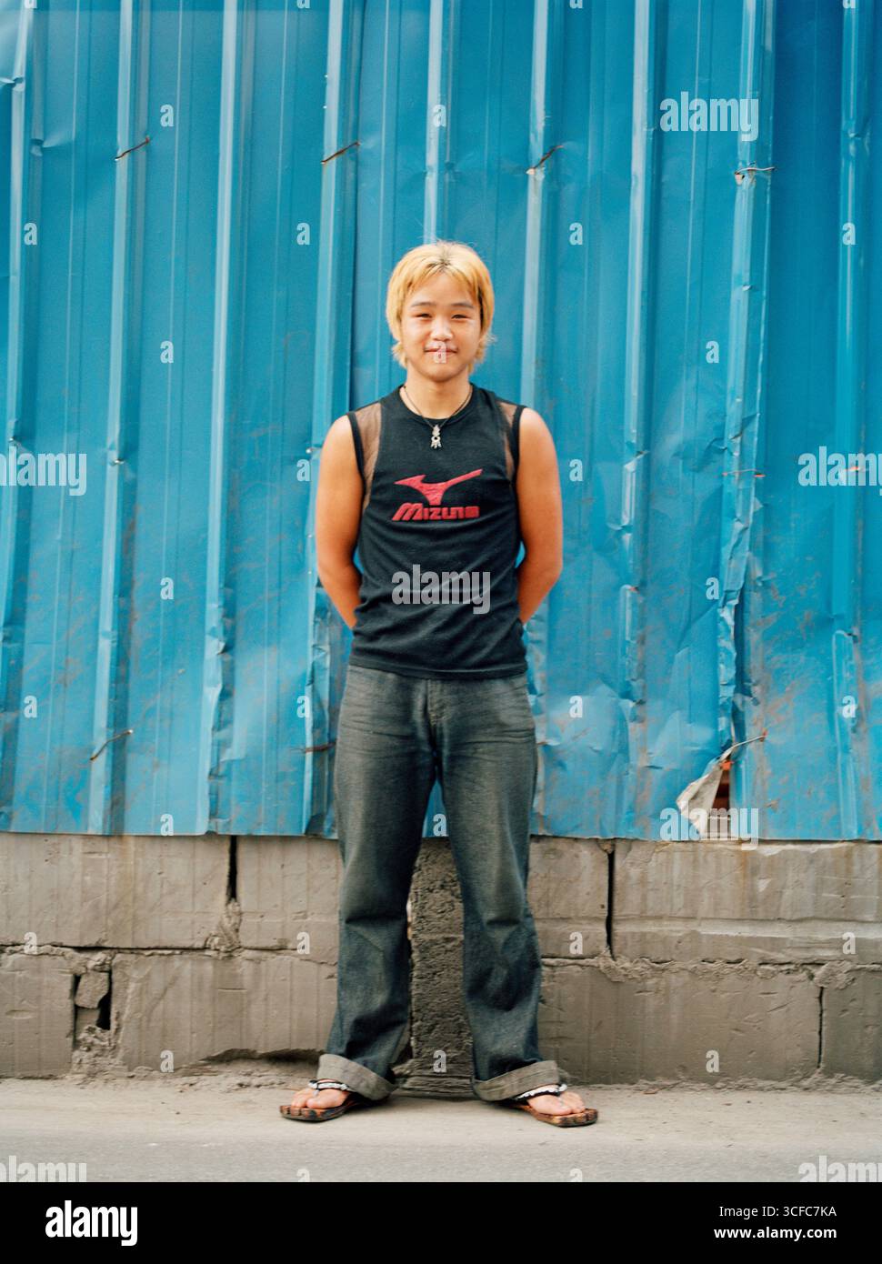 Ein junger chinesischer Teenager in Jeans mit hellgelb gefärbten Haaren Stockfoto