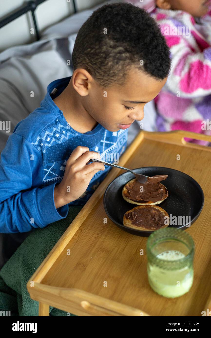 Junge isst im Bett Frühstück Stockfoto