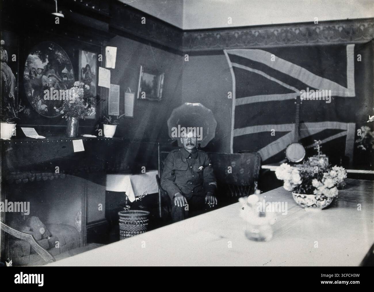 Holmleigh Auxiliary Military Hospital, Harrow: Ein Soldat mit Amnesie sitzt in einem Raum mit einer riesigen Union Jack Flagge an der Wand im Hintergrund, um 1922. Stockfoto