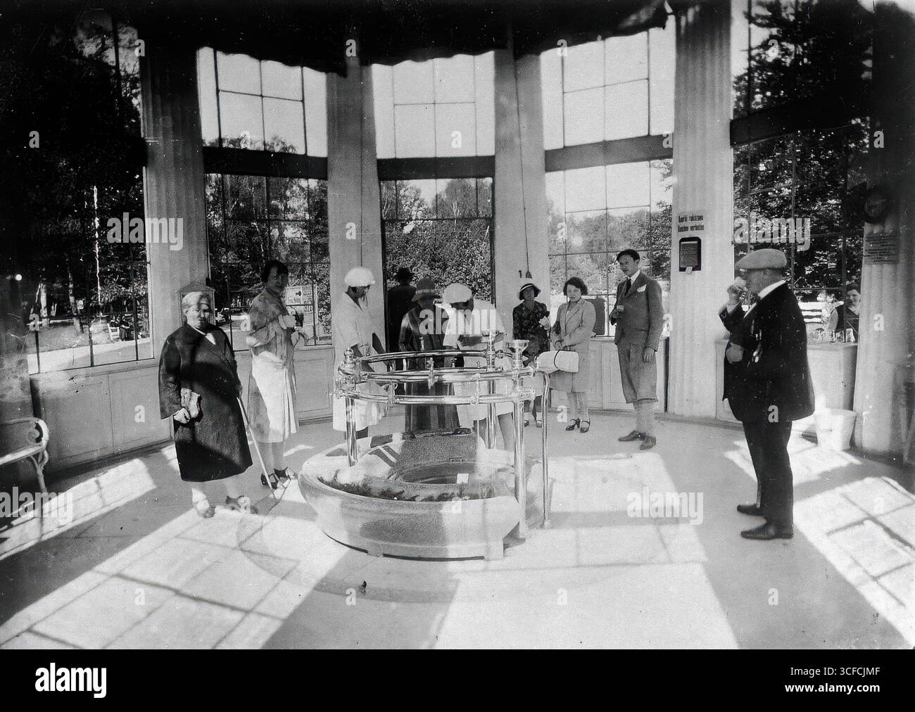 Franzensbad (Frantiskovy L&#xe1;zne), Tschechoslowakei: Das Innere der Franzissohlenquelle, wo Menschen stehen, um Wasser zu trinken, das von weiblichen Pflegerinnen in weißen Uniformen und Kappen aus dem zentralen Kreispunkt gezogen wird, um 1920. Stockfoto