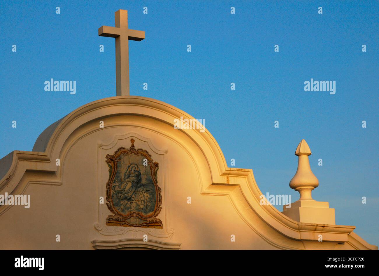 Nossa Senhora das Salas Church, Sines, Portugal, 2008. Architektonisches Detail des oberen Teils der Hauptfassade mit einem Kreuz und einem konischen Gipfel, der die Stützpfeiler der Kirche krönt. Die Kapelle wurde auf Initiative von Vasco da Gama errichtet, neben dem Ort, an dem sich eine Eremitage befand, die an die Rettung von Prinzessin Fatassa erinnert. Der ursprüngliche Tempel stammt aus dem 15. Jahrhundert, wurde aber im 16. Jahrhundert modifiziert. Bezirk von Set&#xfa;bal. Stockfoto