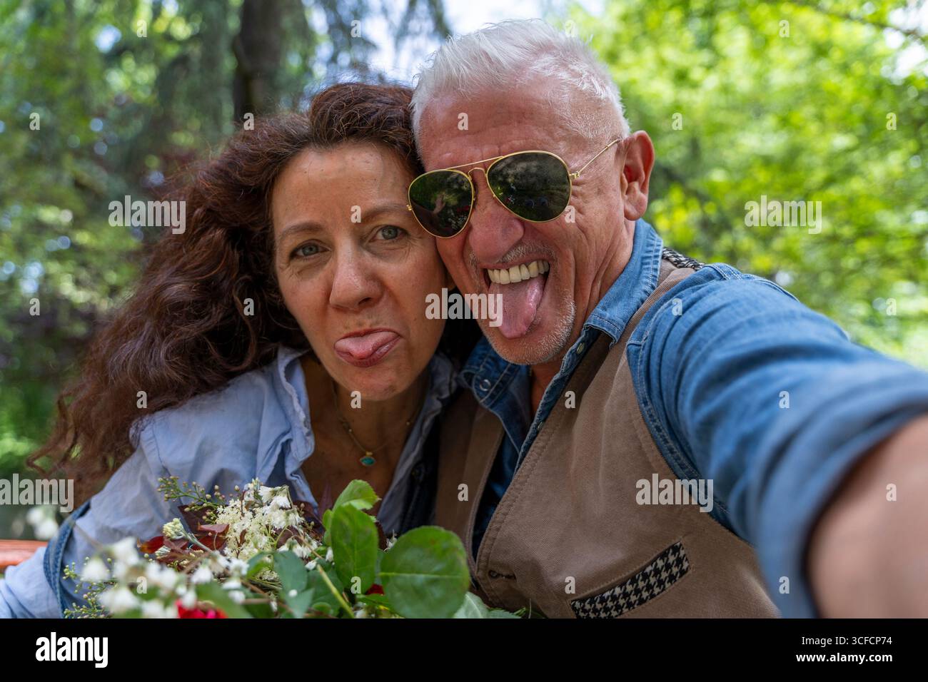 Ein wunderschönes und harmonisches Paar mittleren Alters macht ein lustiges Selfie, um im Freien Gesichter zu machen Stockfoto
