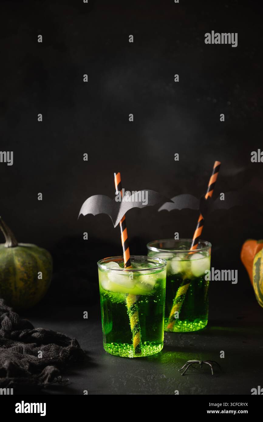 Halloween-Cocktails garnieren lustige schwarze Fledermaus auf schwarzem Hintergrund. Festlicher Drink, gruselige Atmosphäre mit unheimlichen Elementen und verspielter Weihnachtsdekoration Stockfoto
