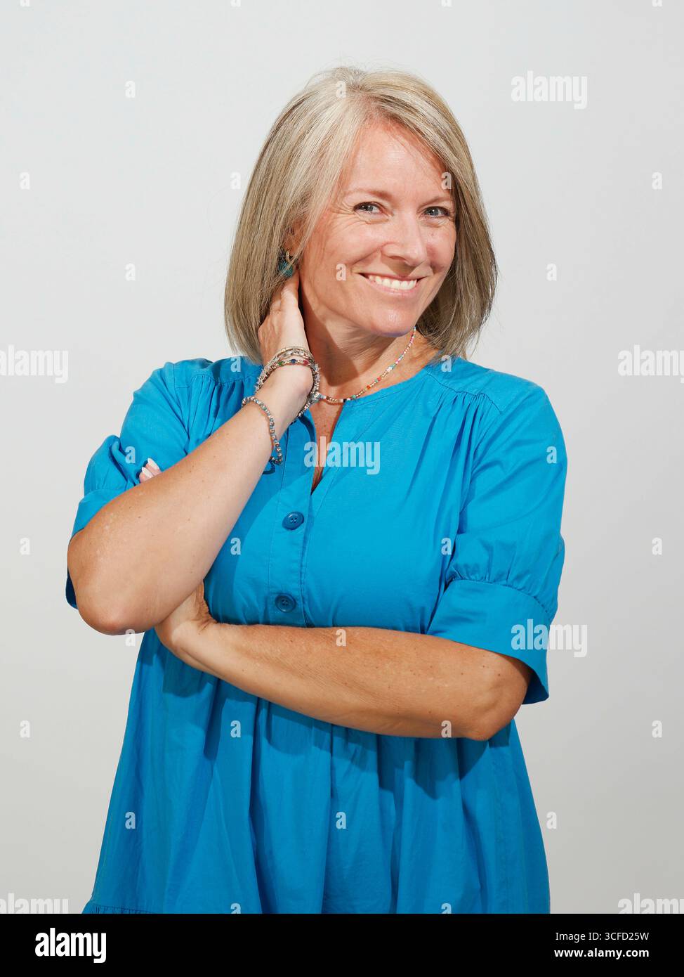 Lächelnde Frau mit grauen Haaren in einem blauen Kleid, posiert selbstbewusst. Italien Stockfoto