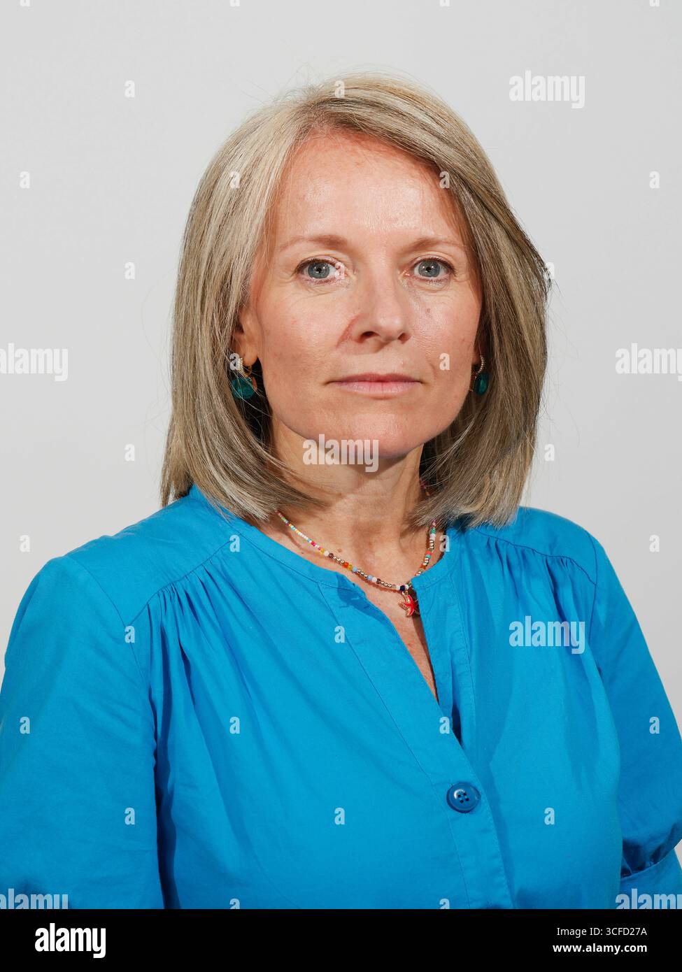 Eine selbstbewusste reife Frau in einem hellblauen Kleid mit überkreuzten Armen vor einem schlichten Hintergrund. Italien Stockfoto