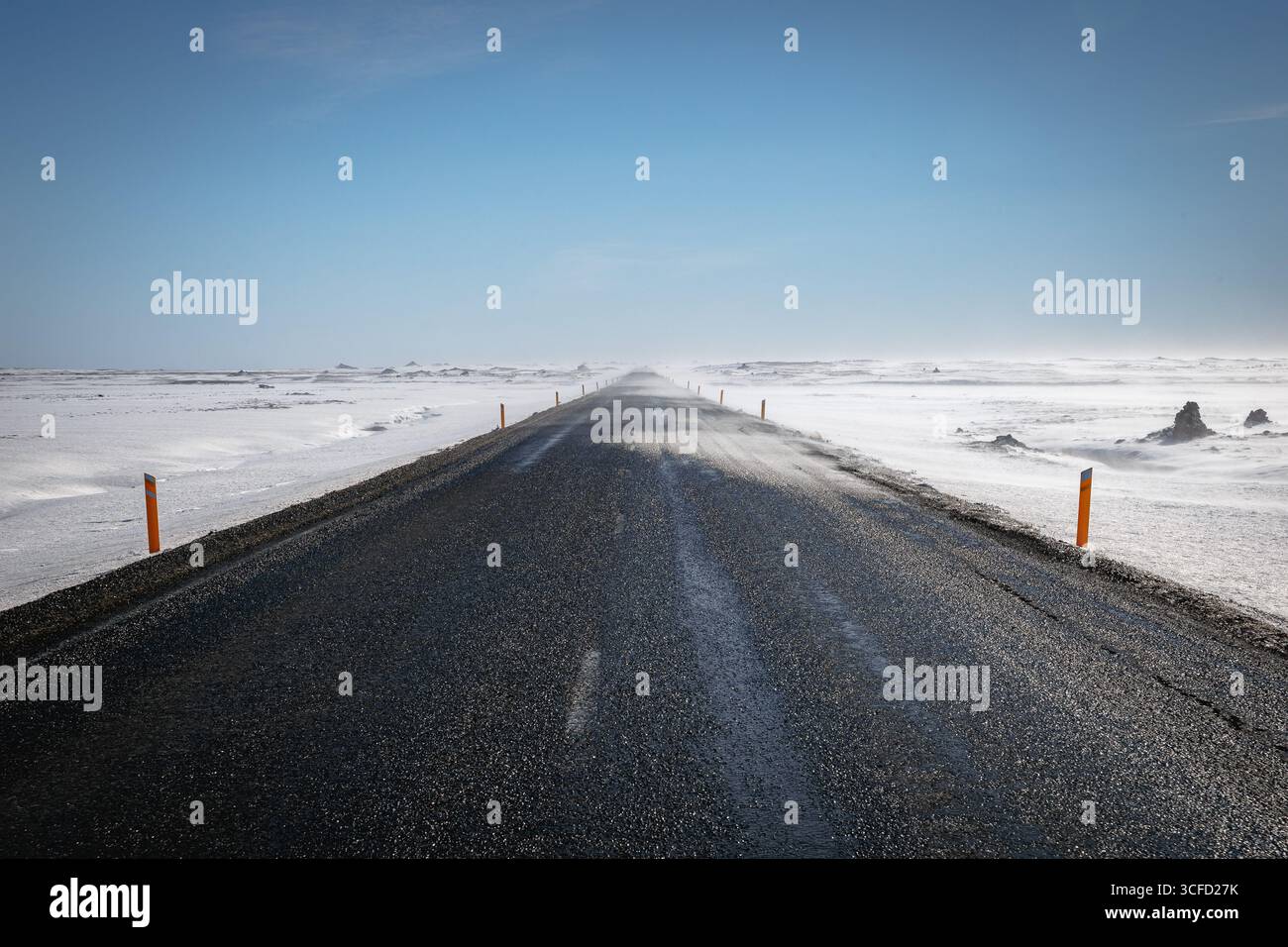 Eine gerade Straße, die im Winter zum Horizont führt, mit Schneewehungen, Island Stockfoto