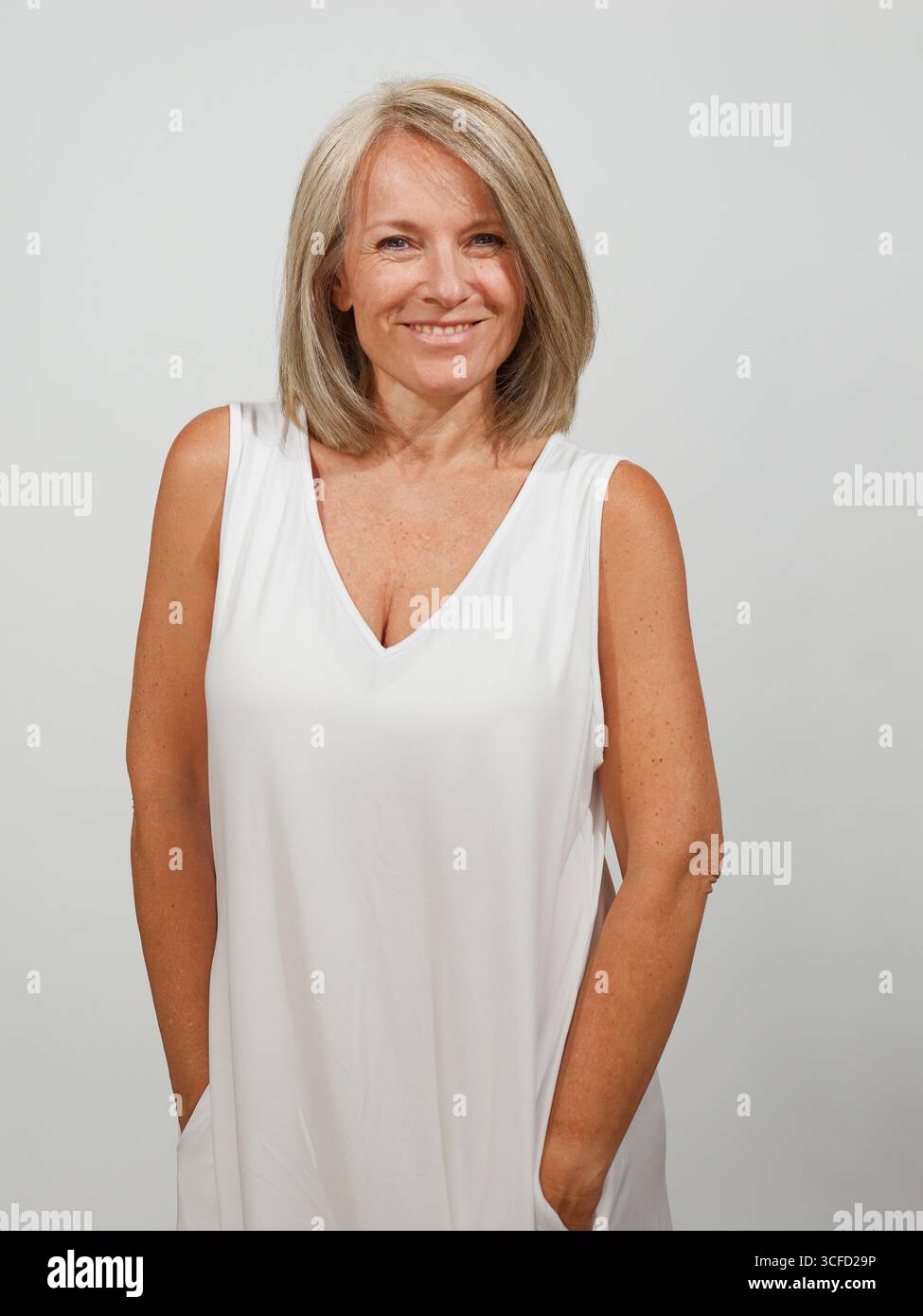 Reife Frau mit einem freundlichen Lächeln, in einem fließenden weißen Kleid, posiert selbstbewusst. Italien Stockfoto