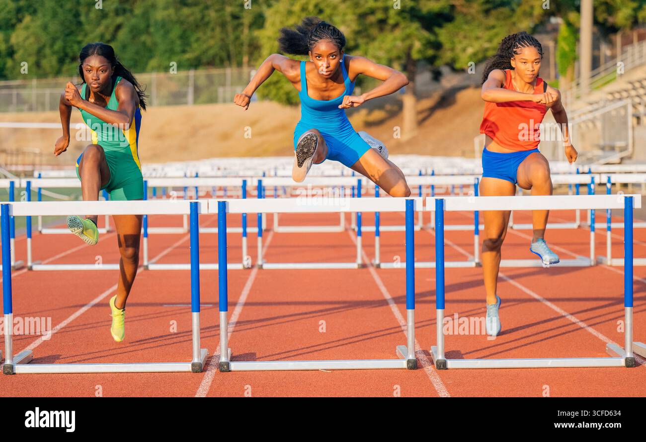 Drei Athleten stürzen sich fachmännisch auf die rote Strecke unter sonnendurchflutetem Himmel. USA Stockfoto