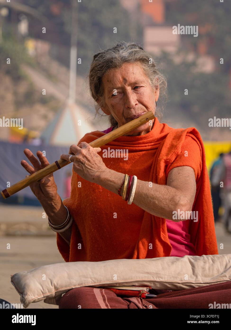 Porträt einer älteren westlichen Frau, die eine Holzflöte auf den Ghats in Varanasi spielt. Stockfoto