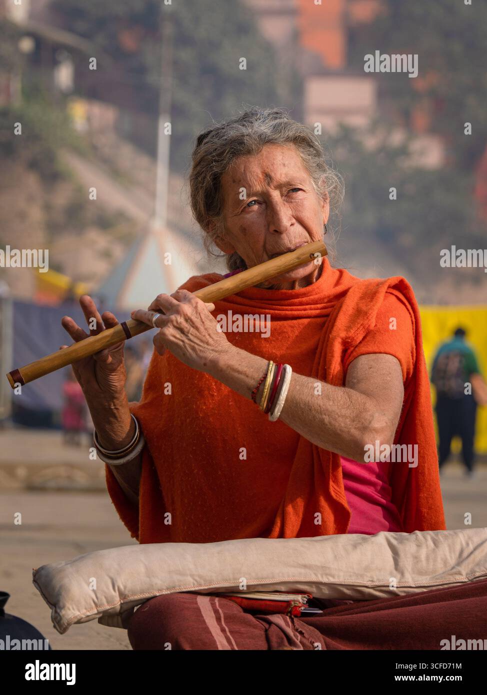 Porträt einer älteren westlichen Frau, die eine Holzflöte auf den Ghats in Varanasi spielt. Stockfoto