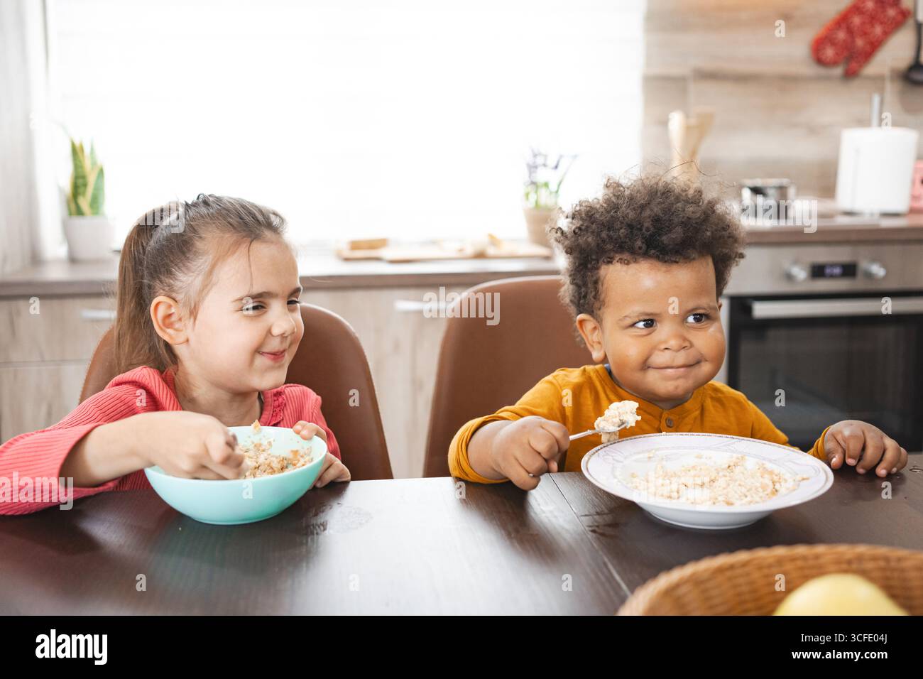 Geschwister mit unterschiedlichem Hintergrund genießen das Frühstück zu Hause Stockfoto