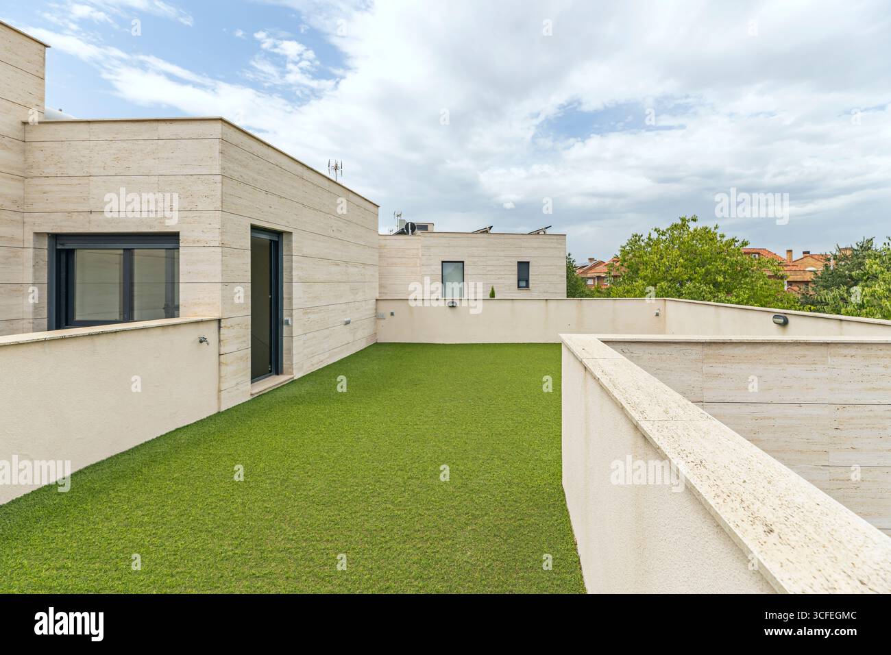 Penthaus-Terrasse, Gesellschaftsbereich mit roter Marmorverkleidung und luxuriösem smaragdgrünem Kunstrasen Stockfoto