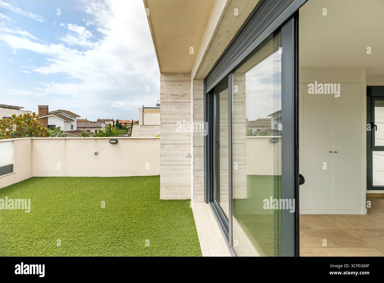 Luxuriöse Penthouse-Terrasse mit weißen Marmorwänden und einem großen Bereich mit dunkelgrünem Kunstrasen Stockfoto