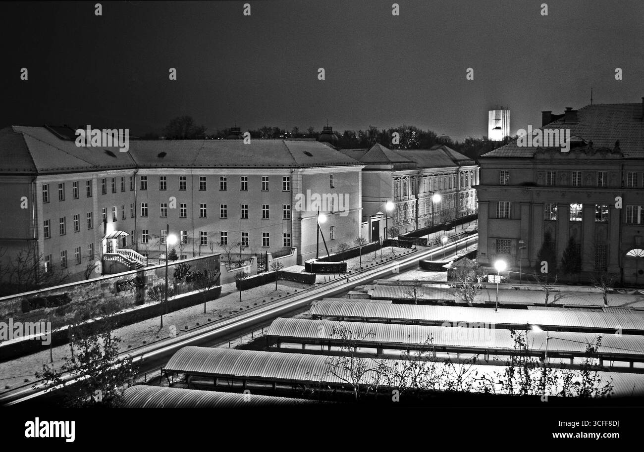 Schwarzweißansicht von einem Balkon über eine ruhige Winternacht in Novi Sad mit alten Gebäuden und einem Teil des Marktes auf Analogfilm. Stockfoto