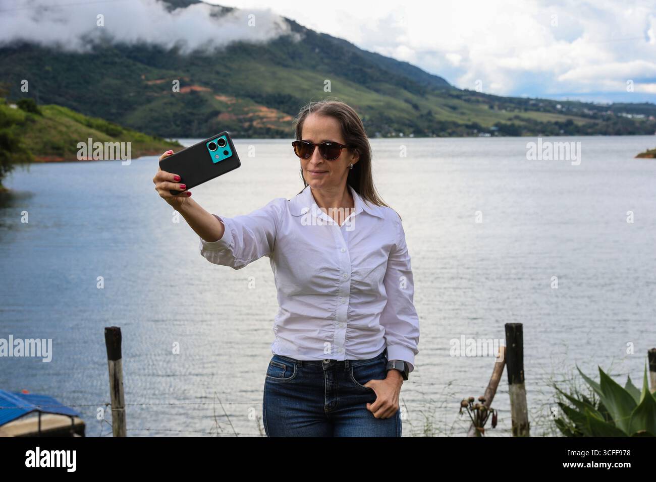 Weibliche Touristen, die Fotos am größten künstlichen See Kolumbiens machen, Calima Lake, der sich in den Bergen von Darien in der Region Valle befindet Stockfoto