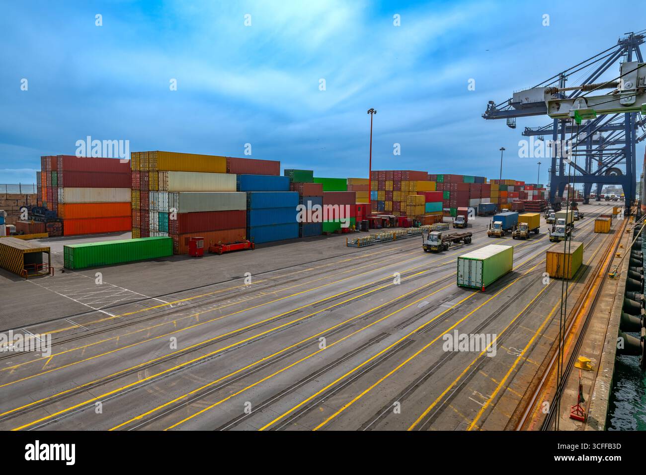 Der belebte Hafen von San Antonio, Chile, mit Containern in verschiedenen Farben, die ordentlich gestapelt sind, und LKWs, die entlang der Docks fahren. Stockfoto