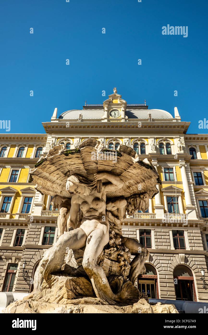 Der monumentale Tritonbrunnen in Triest, Italien, zeigt zwei Tritone und eine Nereide vor dem historischen Neorenaissance-Palazzo delle Poste. Stockfoto