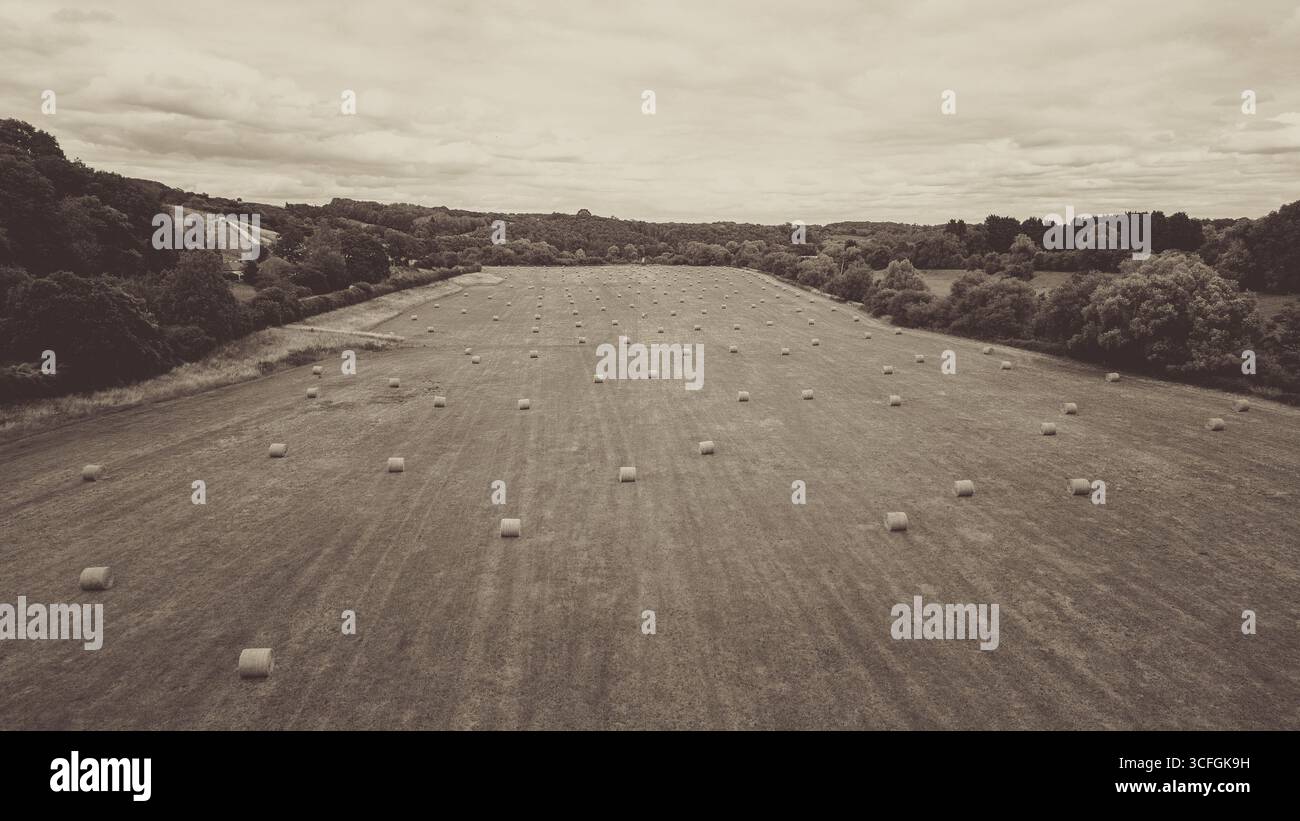 Aus der Vogelperspektive auf Ackerland mit runden Heuballen nach der Ernte in Worcestershire Country, England – ländliche britische Landwirtschaftslandschaft Stockfoto