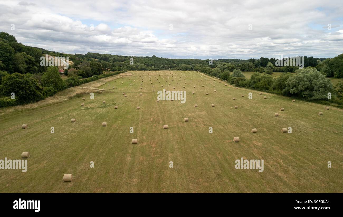 Aus der Vogelperspektive auf Ackerland mit runden Heuballen nach der Ernte in Worcestershire Country, England – ländliche britische Landwirtschaftslandschaft Stockfoto