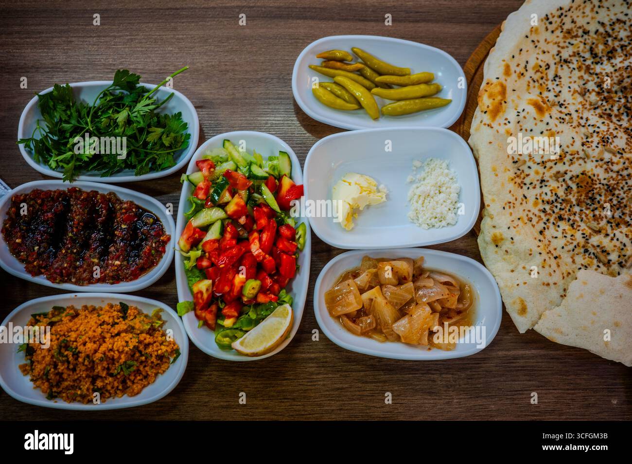 Verschiedene türkische Meze-Gerichte mit frischem Gemüse, Gurken, Dips und Fladenbrot, serviert auf einem Holztisch in Izmit, Kocaeli, Turkiye. Stockfoto