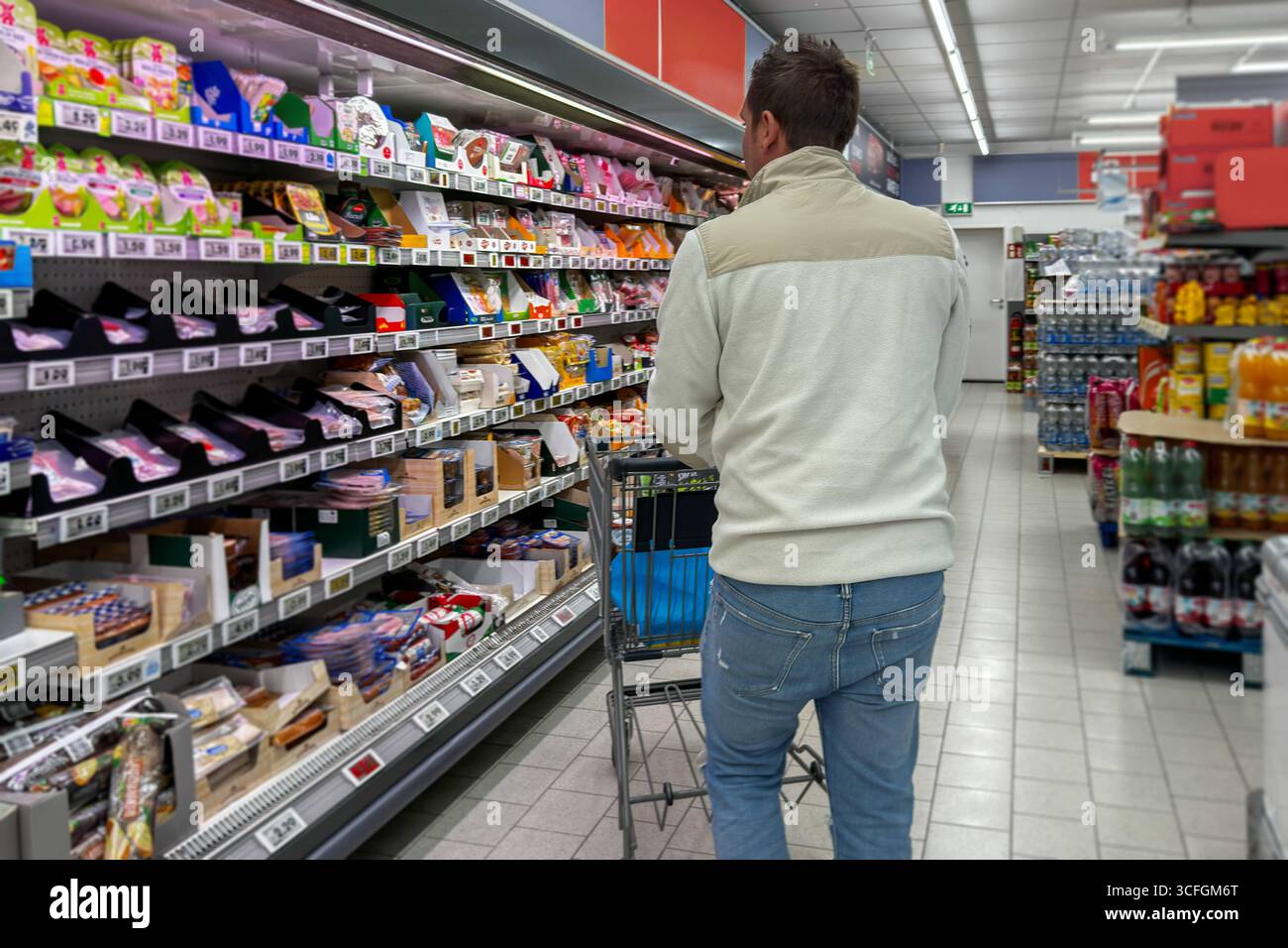 Bayern, Deutschland - 22. August 2025: Ein junger Mann mit einem Einkaufswagen steht vor einem Regal in einem Discounter. Symbolisches Image steigender Lebensmittelpreise, Inflation und Verbraucherbelastung im deutschen Einzelhandel, digital aufgewertet *** ein junger Mann mit Einkaufswagen steht vor dem Regal in einem Discounter. Symbolbild steigende Lebensmittelpreise, Inflation und die Belastung der Verbraucher im deutschen Einzelhandel, digital nachbearbeitet Stockfoto