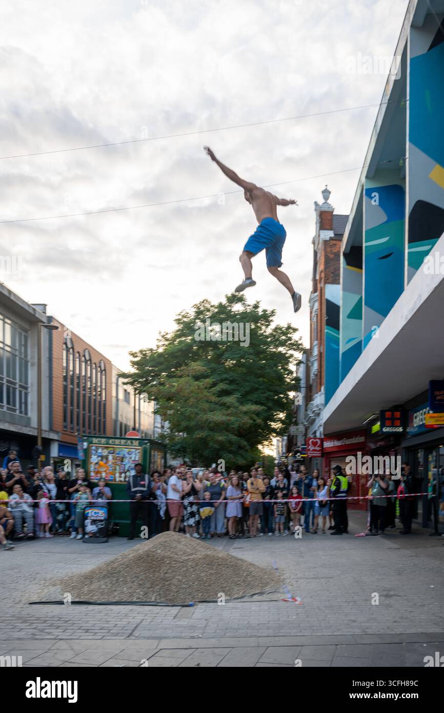 London, Großbritannien, 22. August 2025, begann das Greenwich + Docklands International Festival (GDIF) mit Above and Beyond von Lezards Bleus und The Citizens of the World Choir. Die Menschenmassen überfüllten den Beresford Square in Woolwich, um den acht Darstellern beim Tanz auf den Dächern zuzusehen. Dies ist das 30. Jahr der GDIF, die mit Freilufttheater, Zirkus und Tanz in den Parks feiert. GDIF geht weiter bis zum 8. September. Andrew Lalchan Photography/Alamy Live News Stockfoto