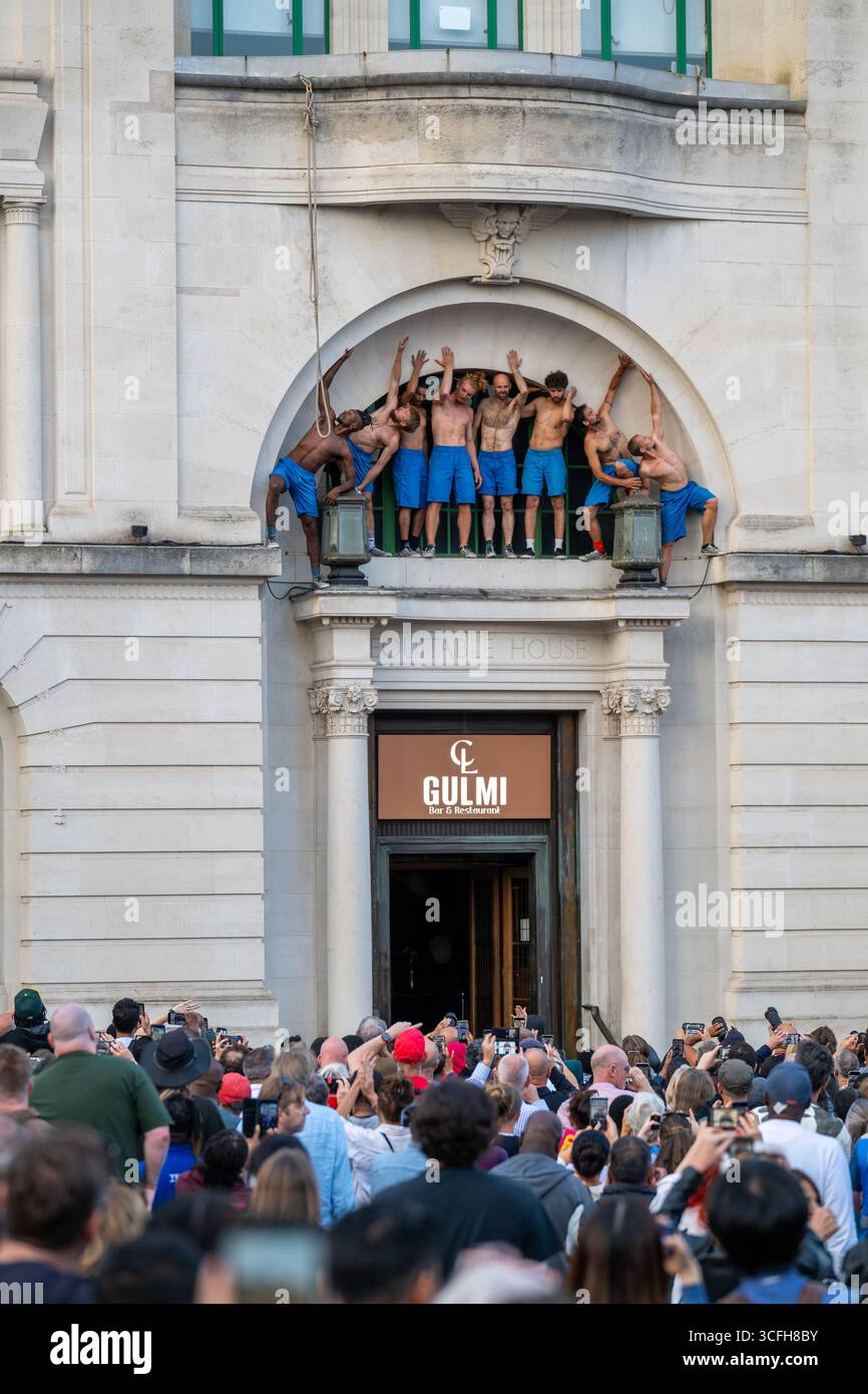 London, Großbritannien, 22. August 2025, begann das Greenwich + Docklands International Festival (GDIF) mit Above and Beyond von Lezards Bleus und The Citizens of the World Choir. Die Menschenmassen überfüllten den Beresford Square in Woolwich, um den acht Darstellern beim Tanz auf den Dächern zuzusehen. Dies ist das 30. Jahr der GDIF, die mit Freilufttheater, Zirkus und Tanz in den Parks feiert. GDIF geht weiter bis zum 8. September. Andrew Lalchan Photography/Alamy Live News Stockfoto