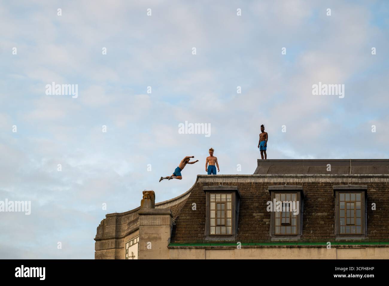 London, Großbritannien, 22. August 2025, begann das Greenwich + Docklands International Festival (GDIF) mit Above and Beyond von Lezards Bleus und The Citizens of the World Choir. Die Menschenmassen überfüllten den Beresford Square in Woolwich, um den acht Darstellern beim Tanz auf den Dächern zuzusehen. Dies ist das 30. Jahr der GDIF, die mit Freilufttheater, Zirkus und Tanz in den Parks feiert. GDIF geht weiter bis zum 8. September. Andrew Lalchan Photography/Alamy Live News Stockfoto