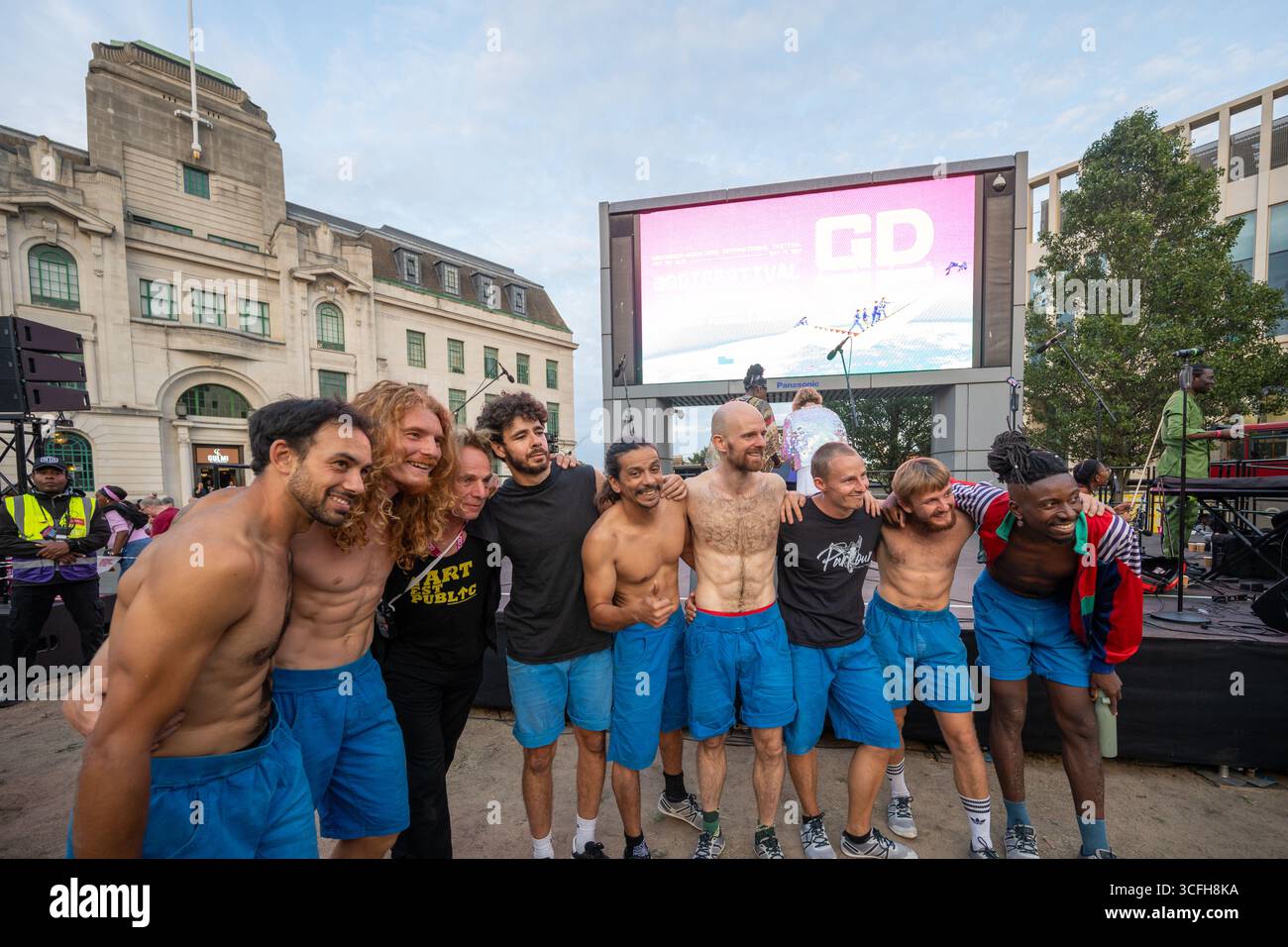 London, Großbritannien, 22. August 2025, begann das Greenwich + Docklands International Festival (GDIF) mit Above and Beyond von Lezards Bleus und The Citizens of the World Choir. Die Menschenmassen überfüllten den Beresford Square in Woolwich, um den acht Darstellern beim Tanz auf den Dächern zuzusehen. Dies ist das 30. Jahr der GDIF, die mit Freilufttheater, Zirkus und Tanz in den Parks feiert. GDIF geht weiter bis zum 8. September. Andrew Lalchan Photography/Alamy Live News Stockfoto