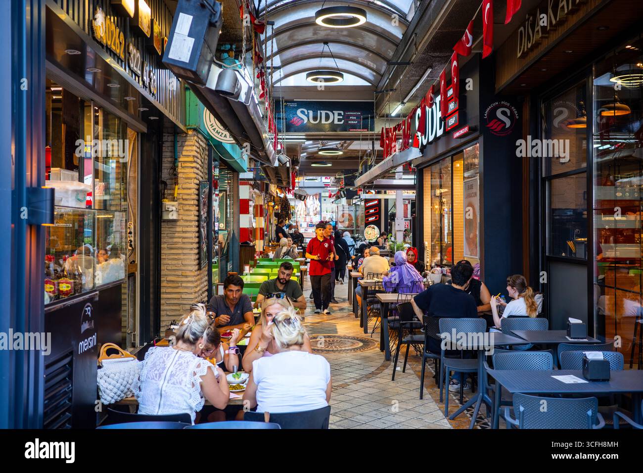 Menschen sitzen an Tischen und genießen Essen auf einem überdachten türkischen Straßenmarkt mit Restaurants und Cafés in Izmit, Kocaeli, Turkiye, am 21. August 202 Stockfoto