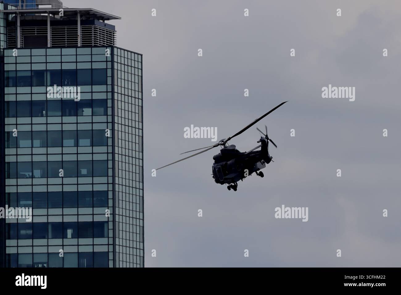 Niederlande Air Force AS532 U2 Cougar Mk2 S-441 fliegt tief über Amsterdam, Niederlande, Nutzungshubschrauber mit offener Seitentür in der Nähe eines modernen Turms. Stockfoto