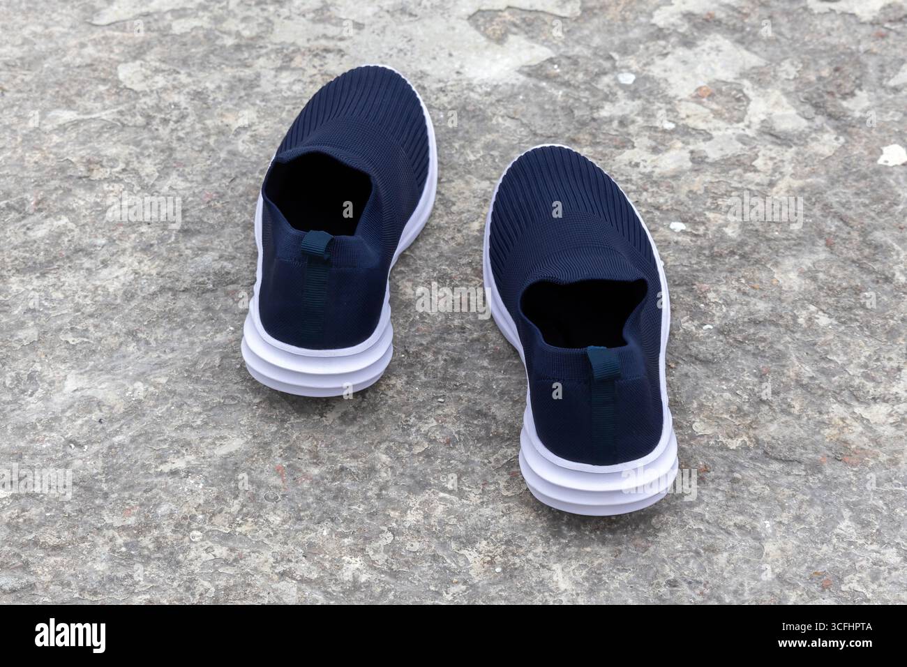 Ein Paar Slip-On-Sneakers für Damen. Bequeme und modische Damenschuhe auf Betonboden, Rückansicht. Stockfoto