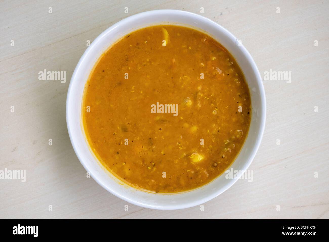 Köstliche rote Linse oder Masoor dal Bhuna oder Ghono dal in einer weißen Schüssel auf hölzernem Hintergrund. Traditionelle Speisen aus Bangladesch und der Region Bengalen Stockfoto