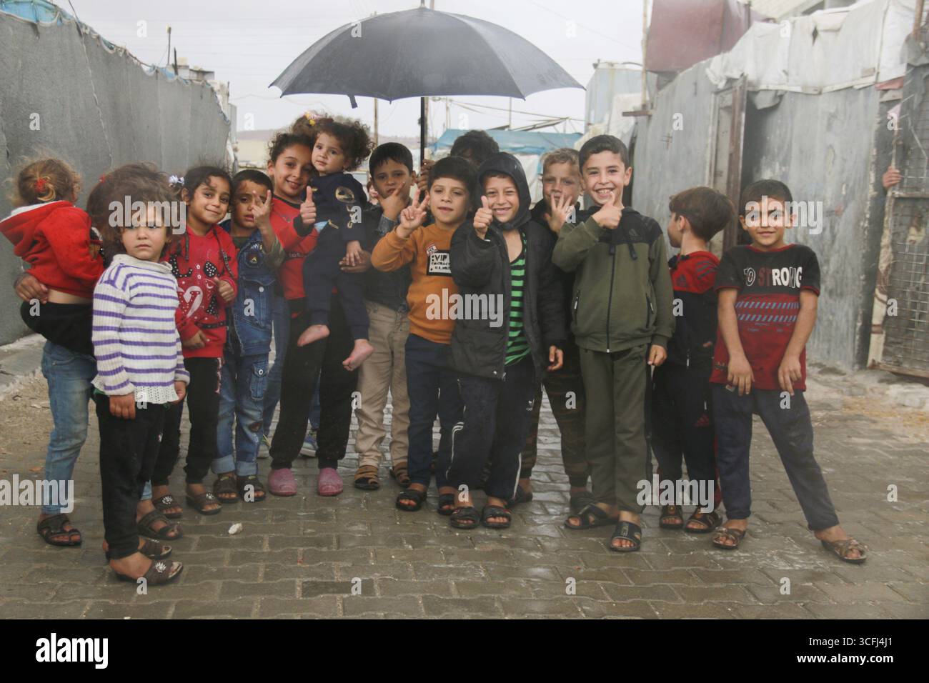 Syrische Kinder im Flüchtlingslager machen ein Gruppenfoto unter dem Regen am Weltkindertag. Aleppo, Syrien, 2. März 2017, Aleppo, Syrien Stockfoto