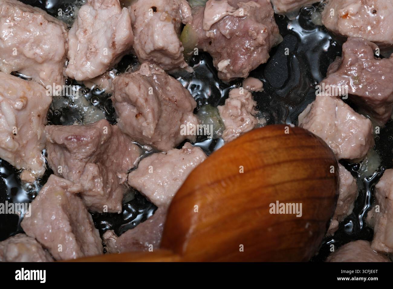 Zarte Fleischwürfel brutzeln in einer heißen Pfanne und geben beim Rühren herzhafte Aromen ab. Stockfoto