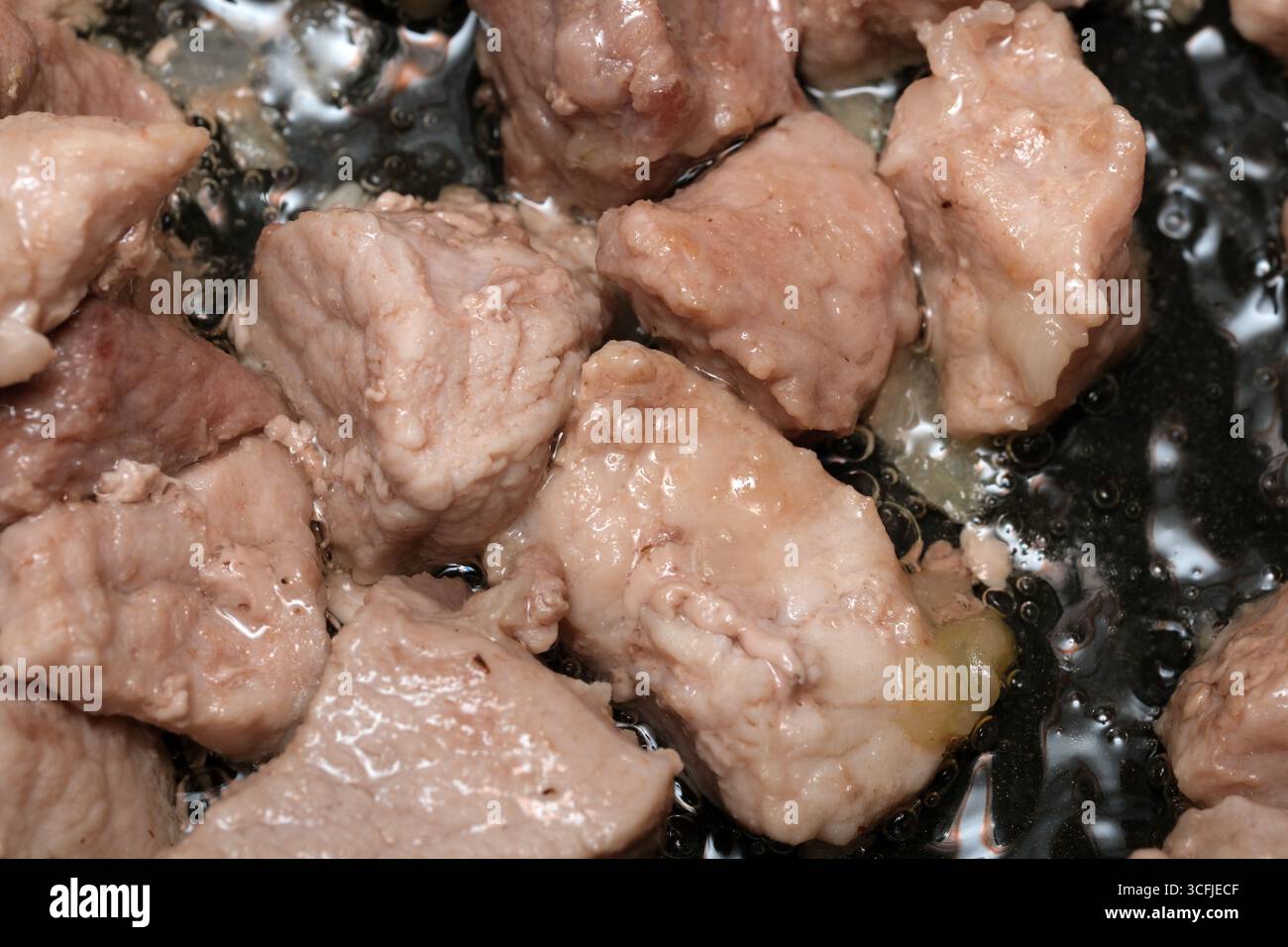 Saftige Fleischstücke werden in sprudelndem Öl gekocht und sorgen für ein unwiderstehliches Aroma zum Abendessen. Stockfoto