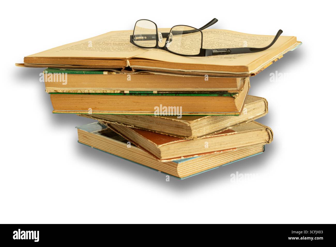 Alte Bücher stapelten sich übereinander, abgenutzt vom Lesen. Das oberste Buch ist gut beleuchtet mit einer Brille auf weißem Hintergrund. Stockfoto