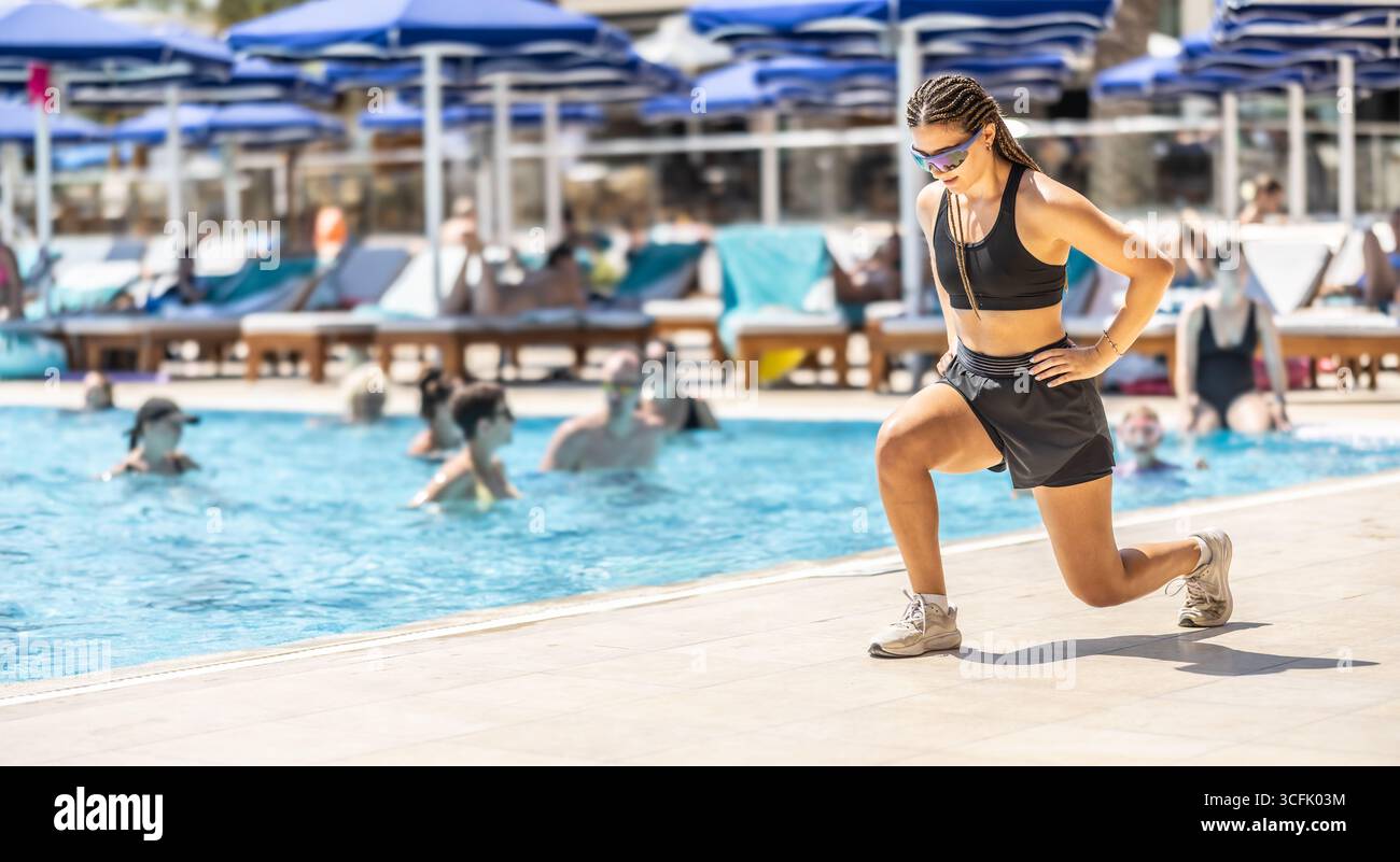 Eine junge weibliche Sportanimatorin macht Wassergymnastik für Menschen im Pool eines Hotelresorts. Stockfoto