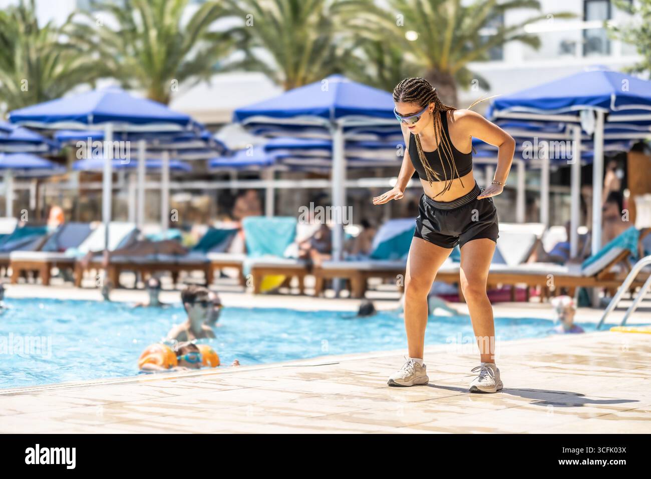 Eine junge weibliche Sportanimatorin macht Wassergymnastik für Menschen im Pool eines Hotelresorts. Stockfoto