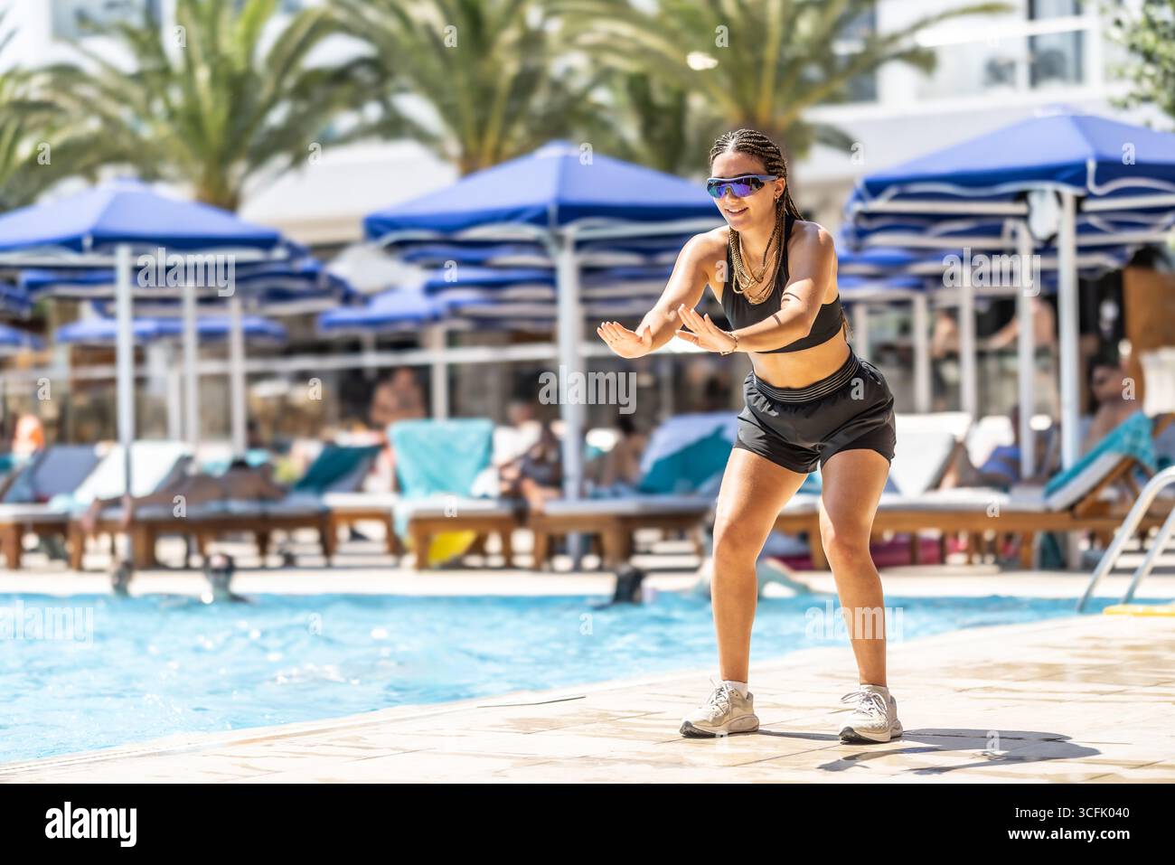 Eine junge weibliche Sportanimatorin macht Wassergymnastik für Menschen im Pool eines Hotelresorts. Stockfoto