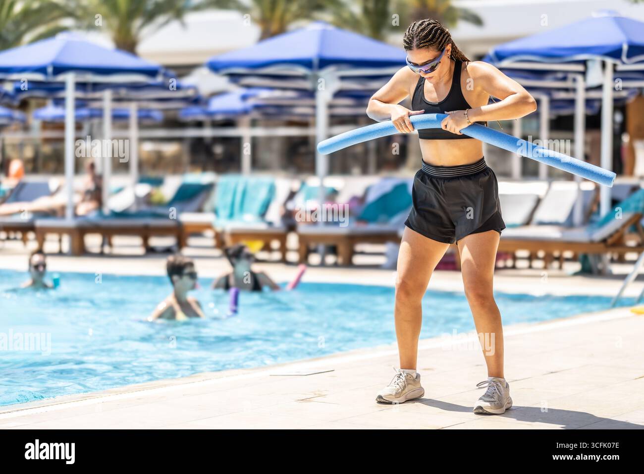 Eine junge weibliche Sportanimatorin macht Wassergymnastik für Menschen im Pool eines Hotelresorts. Stockfoto