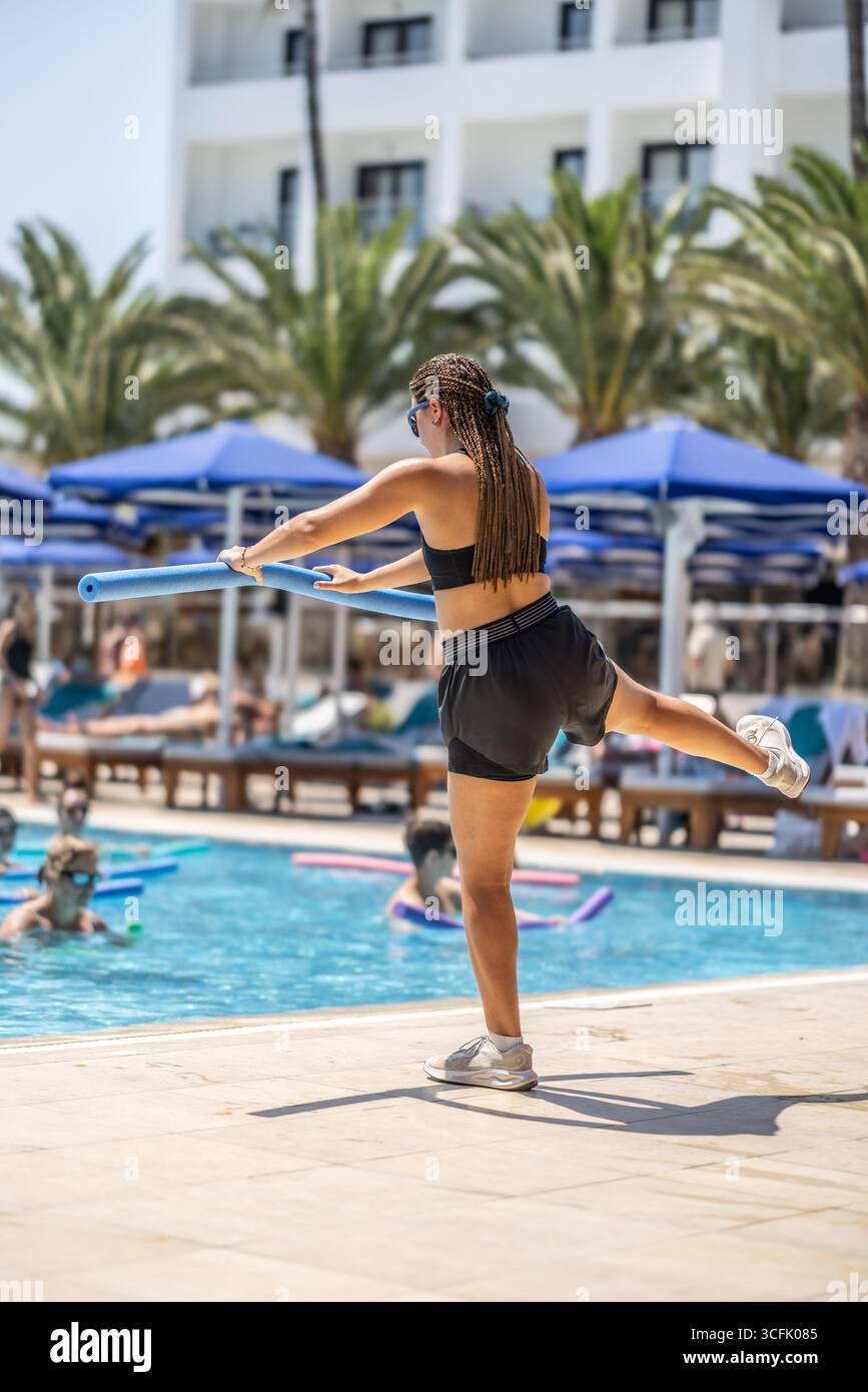 Eine junge weibliche Sportanimatorin macht Wassergymnastik für Menschen im Pool eines Hotelresorts. Stockfoto