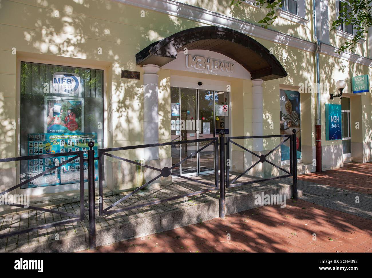 Nagykanizsa, Ungarn - 18. Mai 2025: Moderner Geldautomat der MBH Bank mit blauem Firmenschild, Glaseingang und traditionellen Straßenlaternen mit Stockfoto