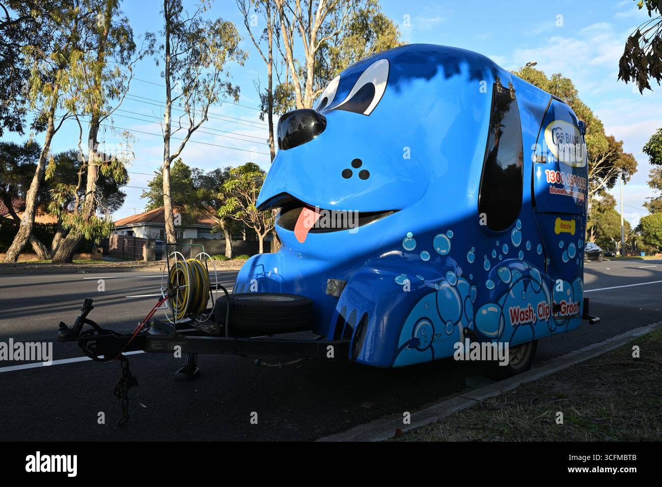 Blauer Hundewäscherei- und Pflegeanhänger der Blue Wheelers, der am Straßenrand geparkt ist, früh am Tag Stockfoto