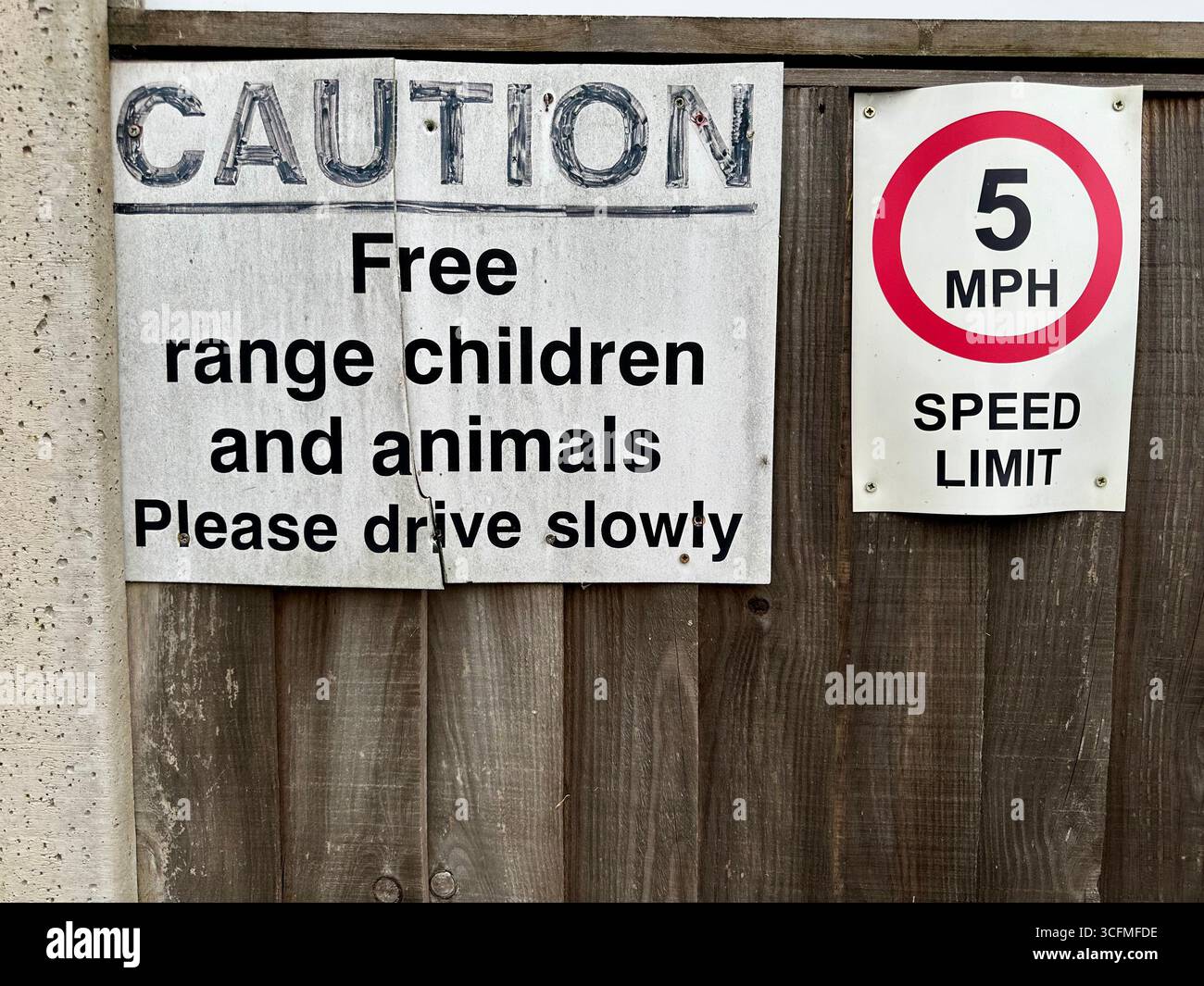 Schilder mit einer Geschwindigkeitsbegrenzung von 5 mph, ein Schild mit der Aufschrift Achtung Freie Reichweite Kinder und Tiere bitte langsam fahren Stockfoto